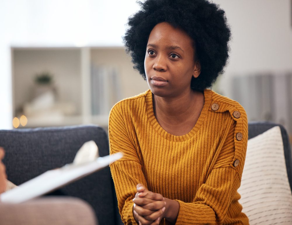 Person in yellow sweater listening attentively indoors.