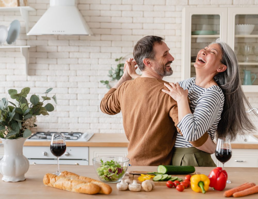 Couple laughing and dancing in kitchen.