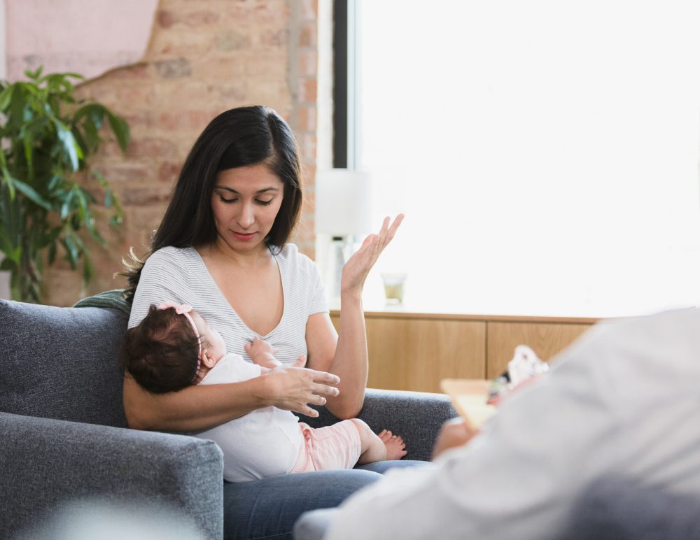 Mother breastfeeding baby on a couch.