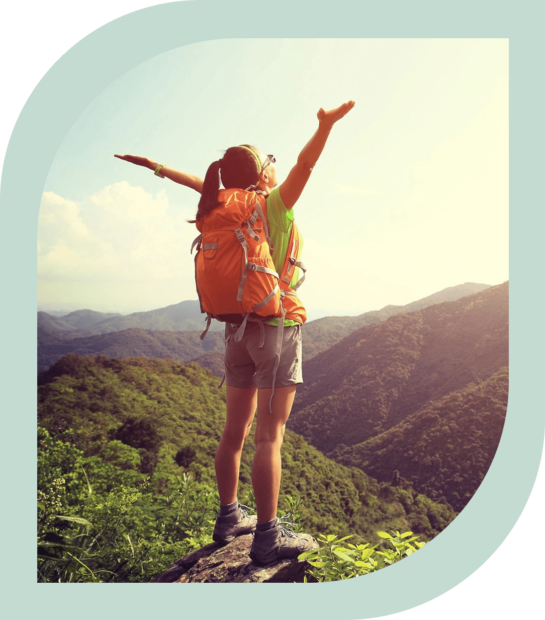 A person with arms outstretched on top of a mountain.